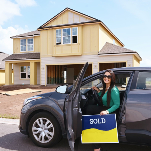 Una persona en un carro sosteniendo un letrero al frente de una casa